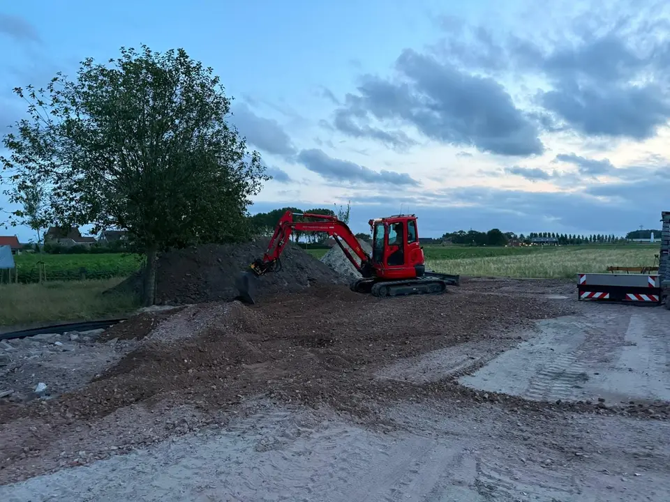 Kraan brengt verhardingsmateriaal aan op het erf