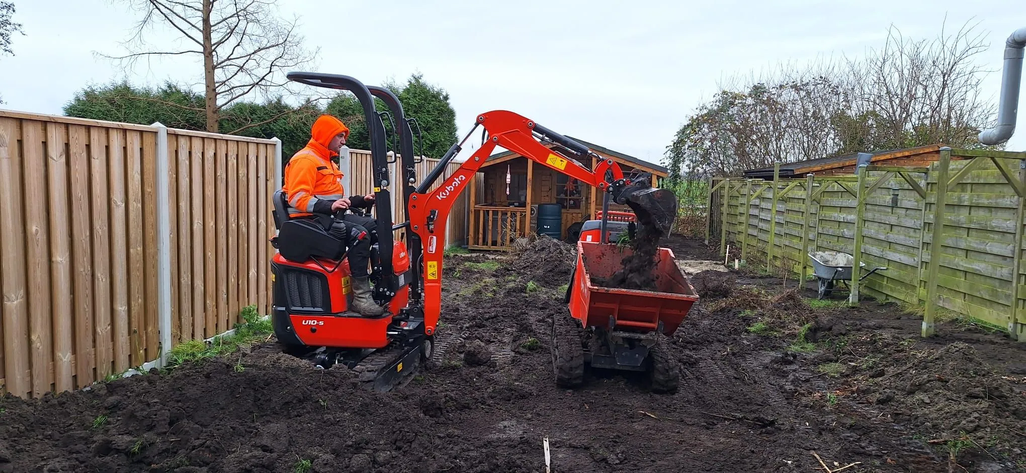 Gert-jan van Cadsand op de minikraan in een achtertuin, met de dumper ernaast