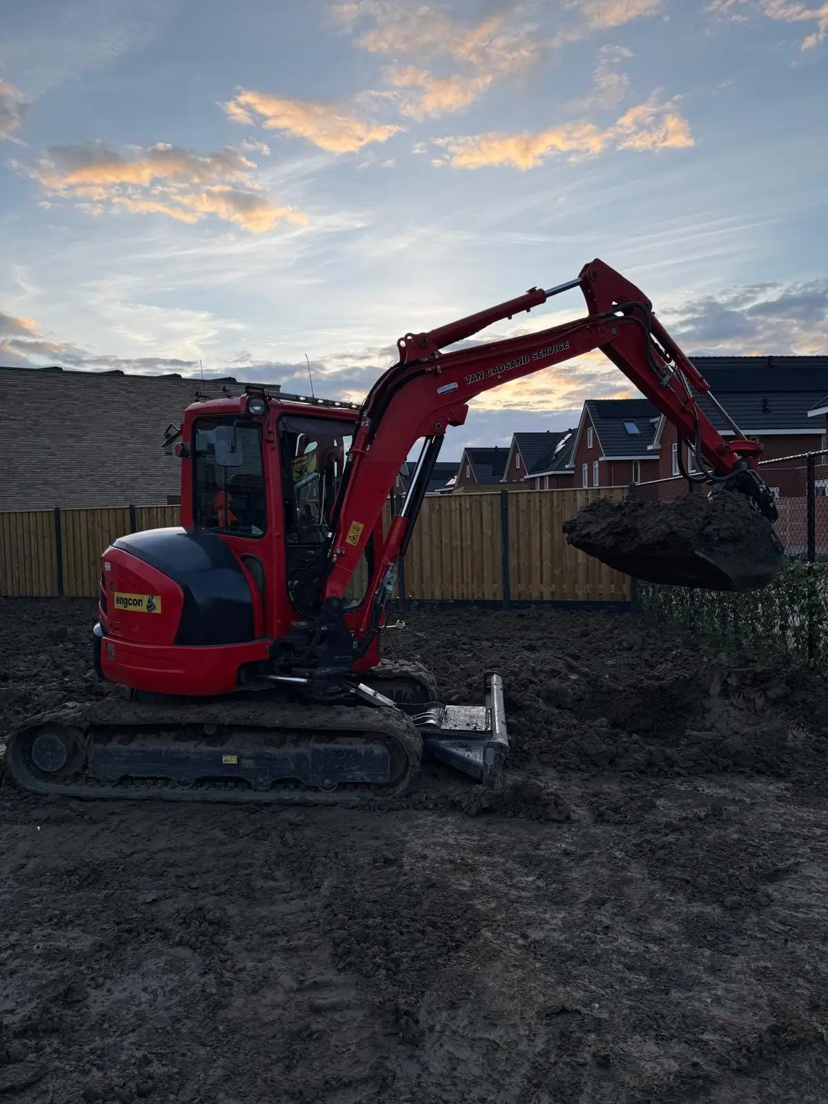 De kraan van Van Cadsand Service op een nieuwbouwperceel bij zonsondergang